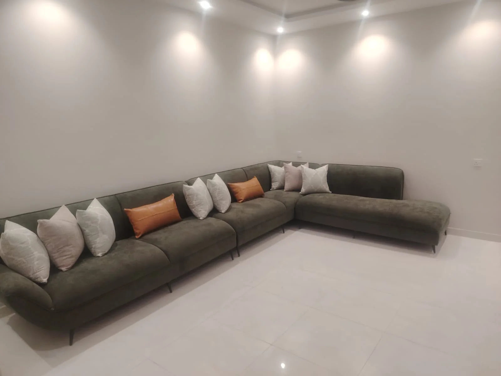 كنب زاوية طويل بلون أخضر زيتي مع وسائد مميزة بلون تان في منزل العميل