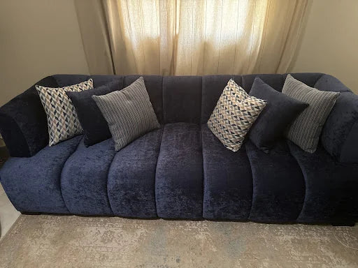 Navy channel sofa by the window — KLIK customer-home photograph