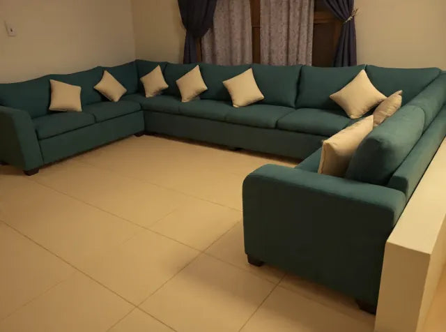 Large teal U-shaped sectional with cream cushions in a customer living room
