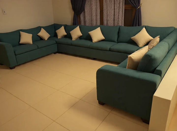 Large teal U-shaped sofa with cream cushions in a customer living room