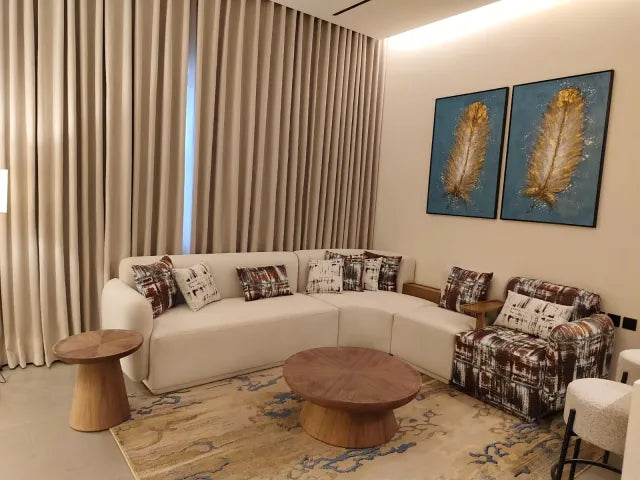 White lounge sectional with patterned chair and wood tables