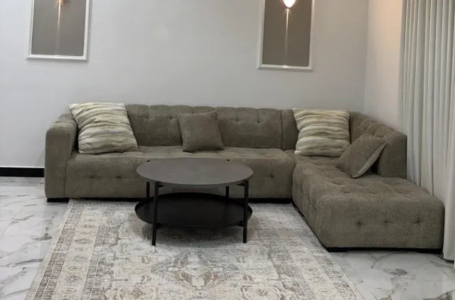 Grey button-tufted sectional with a round coffee table