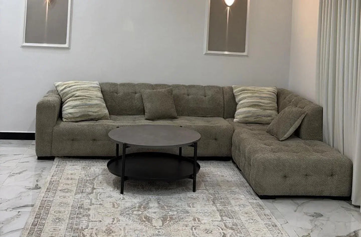 Grey button-tufted corner sofa with a round coffee table