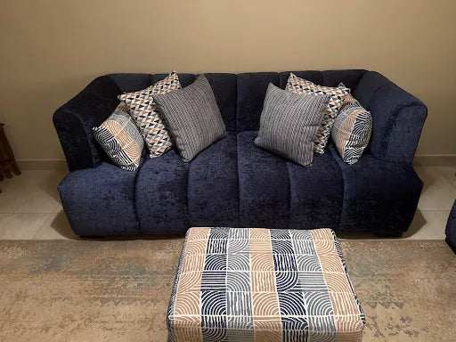 Hassan Albar’s blue sofa with patterned cushions and an upholstered ottoman