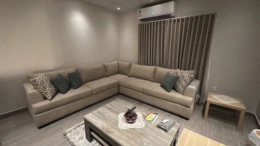 Beige corner sofa with blue and patterned cushions in Mohammed Hindi’s home