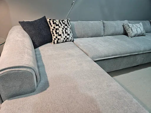 Grey corner sofa with dark and geometric cushions photographed by Vaad Ksa