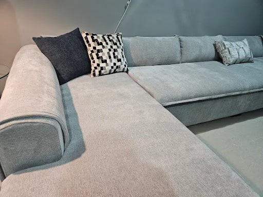 Grey corner sofa with dark and geometric cushions photographed by Vaad Ksa